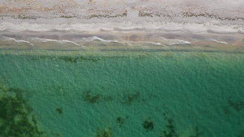 A pristine beach with turquoise waters and gentle waves, aerial view