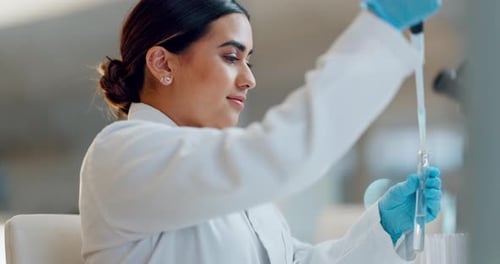 Focused Scientist Pipetting Liquid into Test Tube