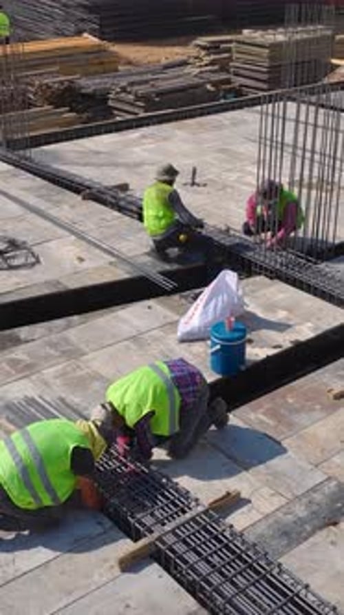 Vídeo vertical Los trabajadores construyen paredes en una concurrida obra mostrando precisión y trabajo en equipo en