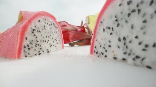 Pitahaya or dragon fruit with white flesh, cut in half. On a white table. Dolly slider extreme close