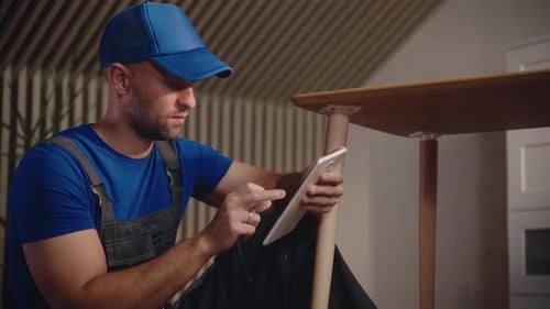 Skilled Worker Using a Tablet to Plan Woodworking Project for Furniture Creation in a Workshop