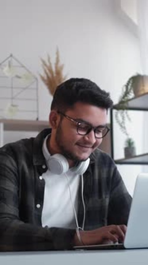 Young Adult Works on Laptop Wearing Headphones