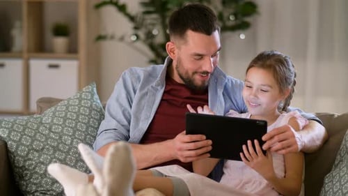 Dad and Daughter Relaxing on Couch with Tablet