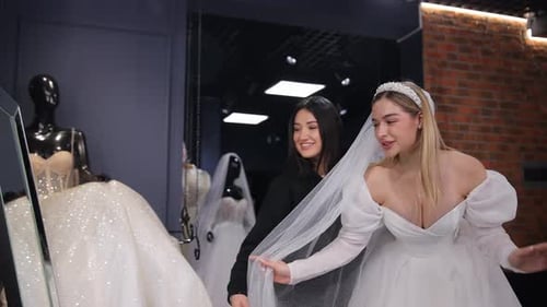 Noiva feliz experimentando um vestido de noiva em um salão de noivas