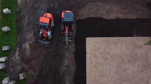 Aerial drone fly over two excavator tractors in a dirt field landscape