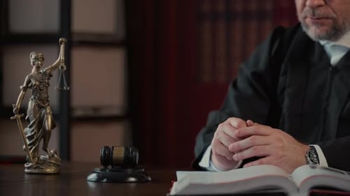 Judge Signing the Document and Strikes Wooden Gavel on Desk After Listening While Statue of Justice