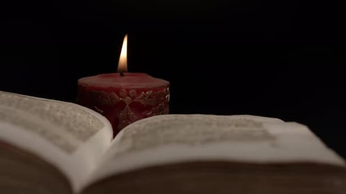 Close up of an open book surrounded by candlelight