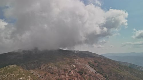 Clouds rolling over a mountain landscape during midday in a serene setting