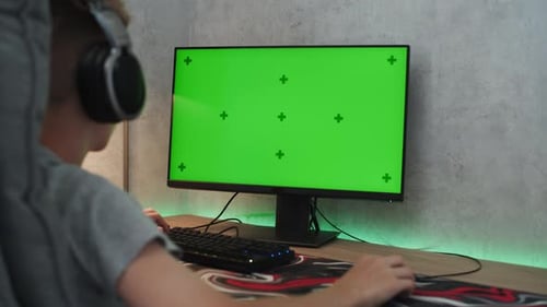 Teen Boy Looks at Personal Computer Monitor with Green Screen