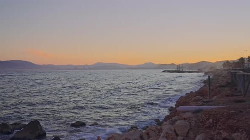 Smooth soft coastline sunset with mountain silhouette on the background