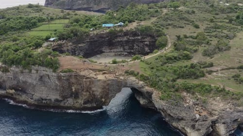 Slow pivot around a cove with a natural archway connecting to the ocean, Aerial shot. Broken Beach,