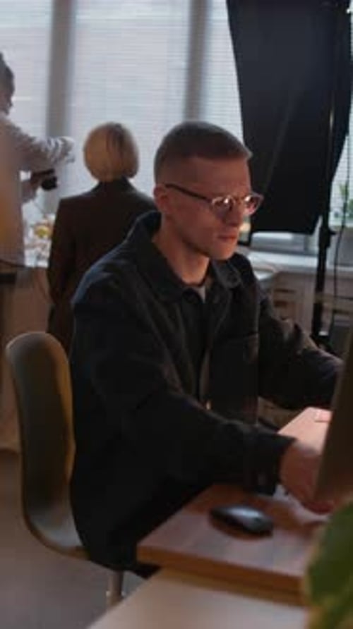 Man Designs on Tablet at Desk in Office