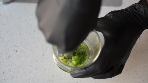 Closeup Highangle View of Bartender in Black Gloves Mashed with Muddler Kiwi and Lemon Slices in a