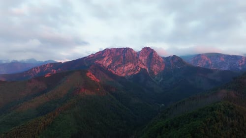 Panoramic mountain view, the setting sun turns the mountain tops red. A calm and beautiful evening i