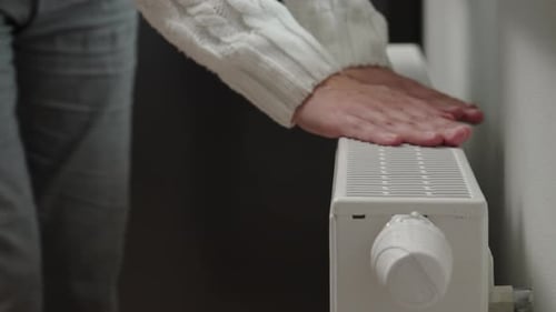 Woman in Warm Sweater Adjusting Temperature on Heating Radiator