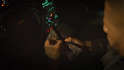 a black man sitting in the drivers seat of a car opens his wallet to find it is empty and throws it