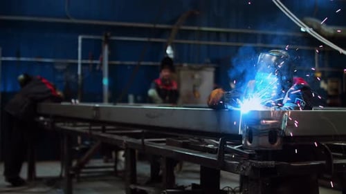 Ein Industriearbeiter ist in einer Fabrikwerkstatt mit dem Schweißen von Metall beschäftigt