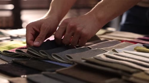 Man's Hands Sort Through Luxurious Fabric Samples