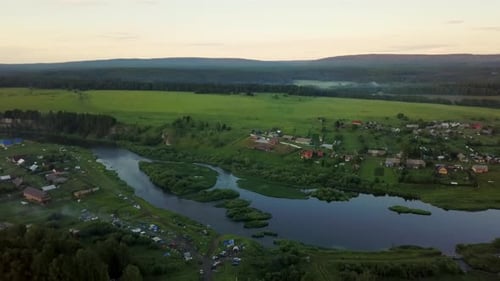 A Beautiful Scenic Landscape Featuring a Picturesque River and a Charming Village at Dusk Stock Clip