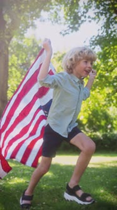 Joyful Boy Running with American Flag in Park