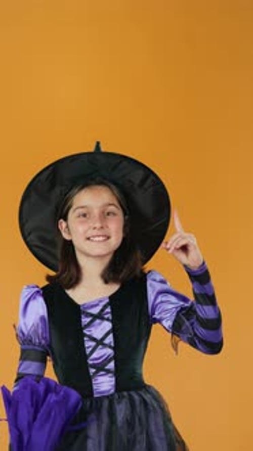 Girl in Witch Costume Against Orange Background
