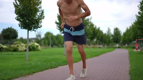 Muscular Man Jogging in the Park on Sunny Day