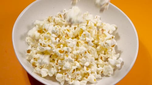 Tossing Salted Popcorn into a Ceramic Bowl. Shot with High Speed Camera. Slow Motion Snack
