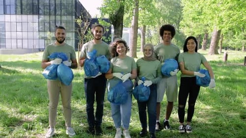 Portrait of multiethnic group of volunteers with garbage bags after cleaning city park.