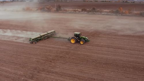 Landwirtschaftlicher Traktor pflügt, arbeitet auf dem Feld. Wir fliegen über einen Traktor, der in der