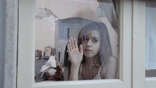 Child Stands at Window Looking Out