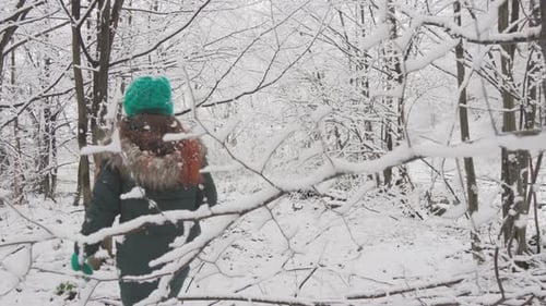 Woman Walking Through a Snowy Forest