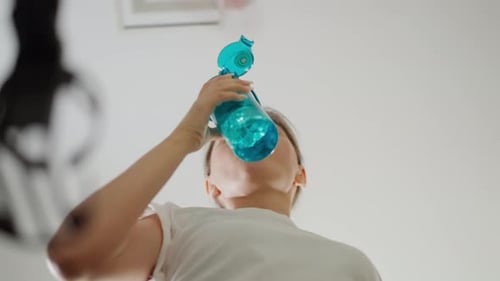 Woman Drinks Water Running on Treadmill in Gym