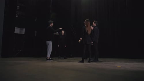 El director de un hombre moreno seguro de sí mismo les dice a los actores de teatro cómo comportarse y conducir sus diálogos