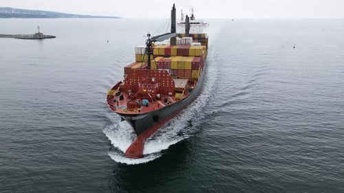 Aerial View of a Large Cargo Ship Carrying Colorful Containers Approaching the Port Maritime