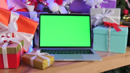 Laptop chromakey on screen, place for ad offers, lying on table among Christmas gifts