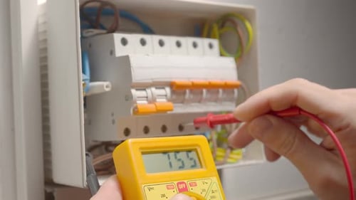 Close up of a mans hands testing white switch box check voltage switchboard