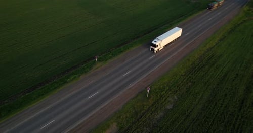 White Truck with a Semi Truck is Driving Along the Highway Aerial Shot