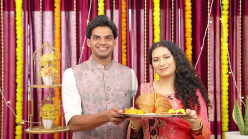 Smiling Couple Holding Diwali Offerings Indoors