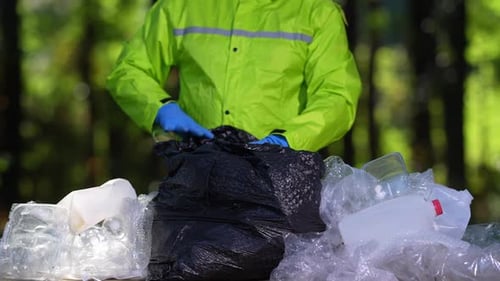 Person Recycling Plastic Waste in Green Jacket