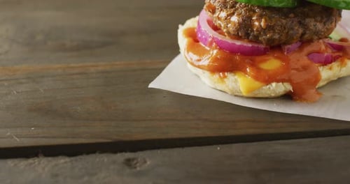 Video of hamburger with salad and relish in burger bun on wooden table top, with copy space