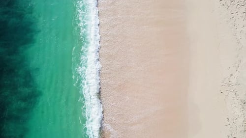 Aerial Top Down View of Turquoise Ocean Waves on White Sand Beach