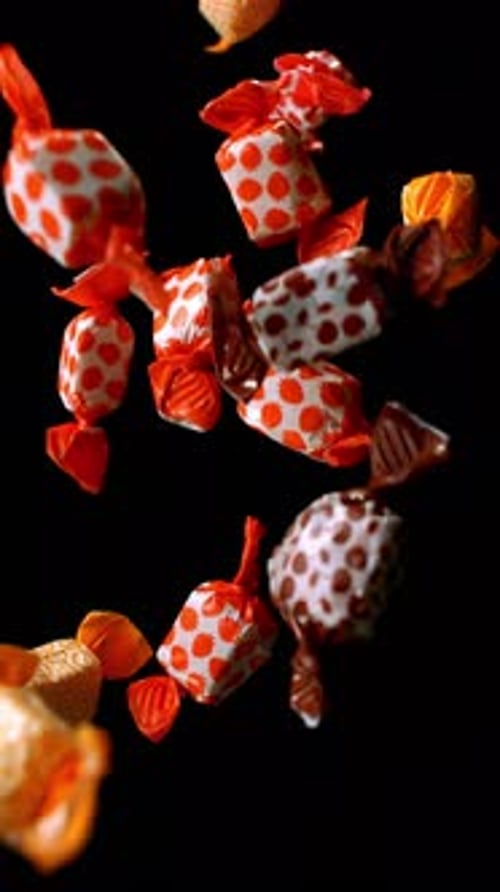 Delicious Wrapped Candies Falling on Black Background