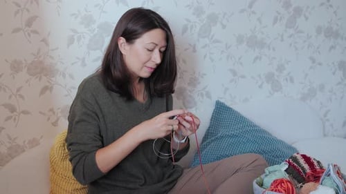 Woman Sits and Knits with Red Yarn