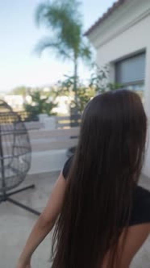 Une jeune femme est dehors sous la lumière du soleil en train de jouer avec une balle bleue entourée d'arbres verts