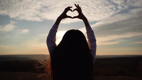 Kind macht Herz Hände gegen den blauen Himmel Kinderhände formen eine Herzform mit Sonnenuntergangs-Silhouette