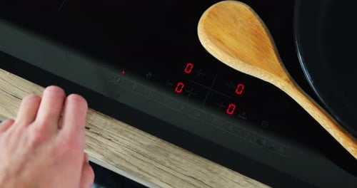 Hand Turns On Modern Touchscreen Cooktop