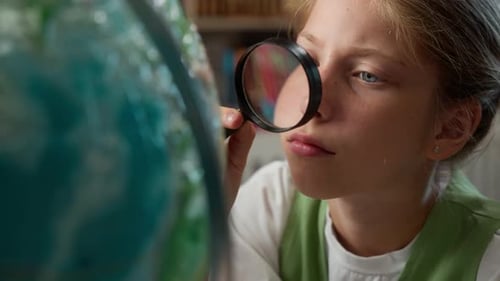 Close Up Concentrated Caucasian Little Girl Child Kid Schoolgirl Looking at Globe with Magnifier