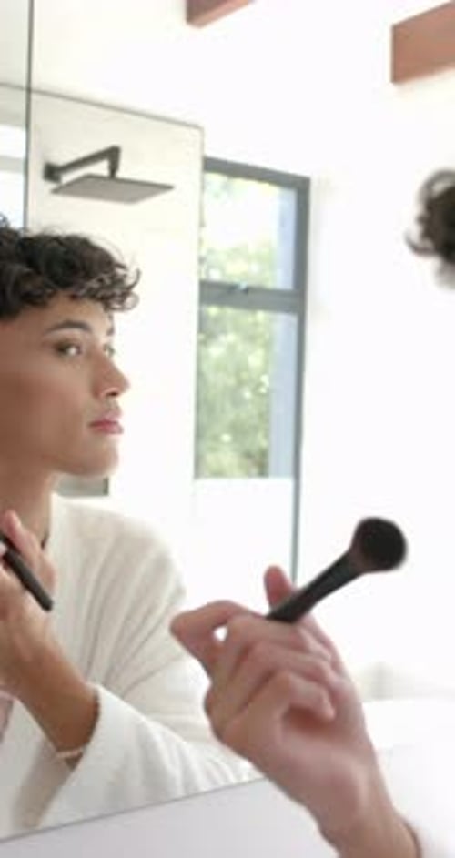 Young Adult Applying Makeup in Bathroom Mirror