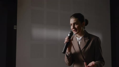 Woman Speaking Into Microphone Giving Business Presentation