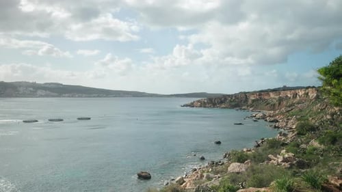 AERIAL: Flying off the Cliff into Mediterranean Sea in Mellieha with Fish Farming Nets Placed in Bay